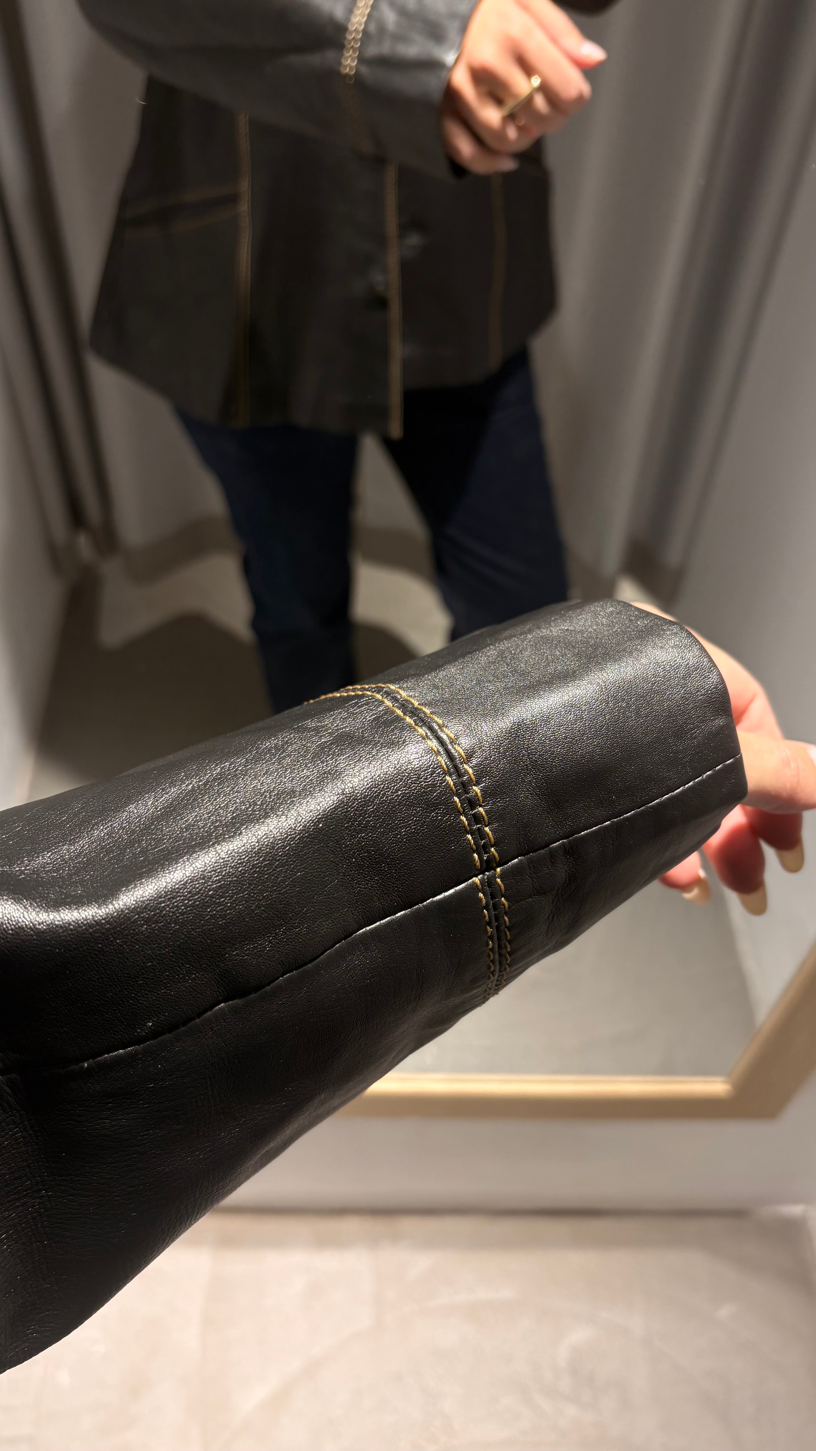 Black natural leather blazer with visible seam detailing and a cinched waist.